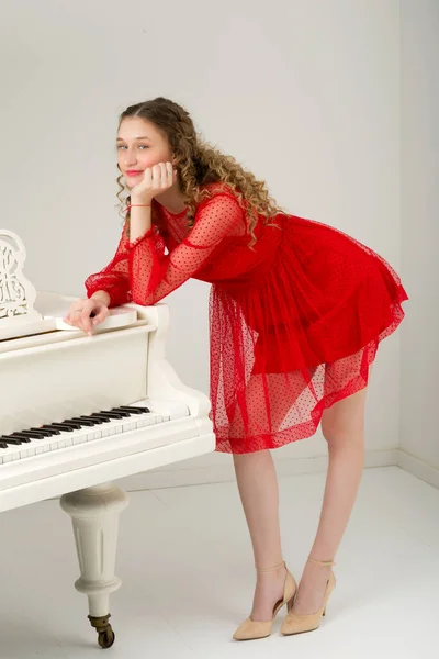Feliz sonrisa elegante chica posando en el piano de cola —  Fotos de Stock