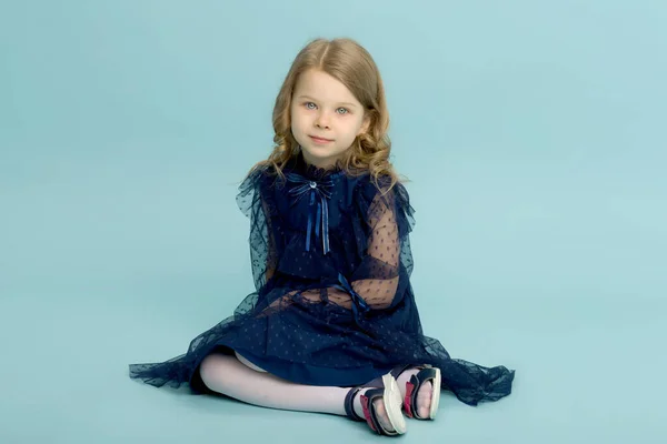 Gelukkig klein meisje in blauw jurk zitten op de vloer — Stockfoto