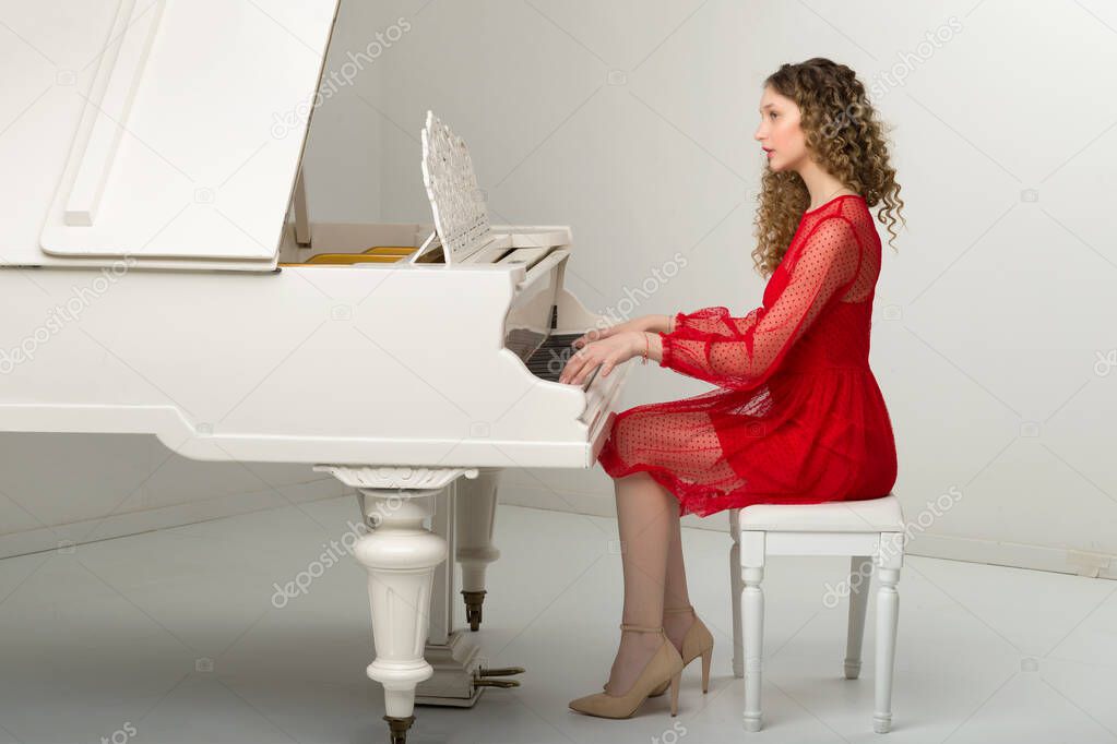 Pretty blonde young woman play white grand piano