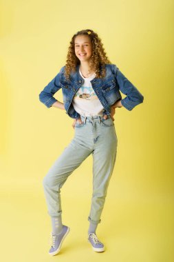 Güzel kız, elleri belinde poz veriyor.