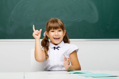 Okullu kız parmağıyla işaret edip yukarı bakıyor.