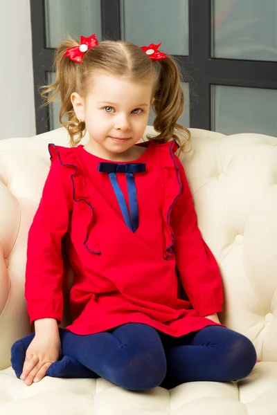 Cute blonde little girl sitting on comfy armchair — Stock Photo, Image