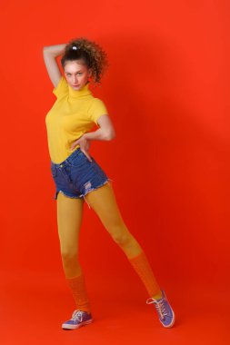 Güzel fitness kızı kırmızı arka planda rahatça poz veriyor.