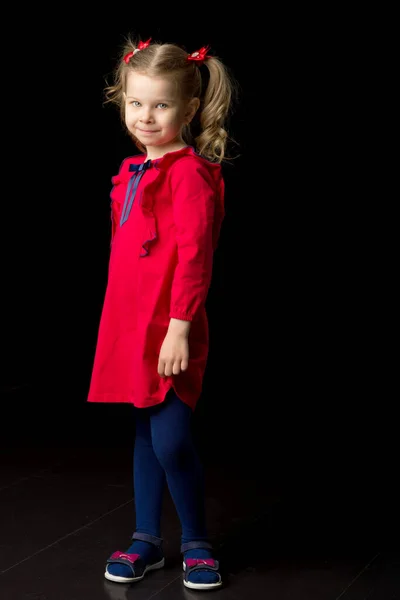 Cute blonde little girl standing on black backdrop — Stock Photo, Image