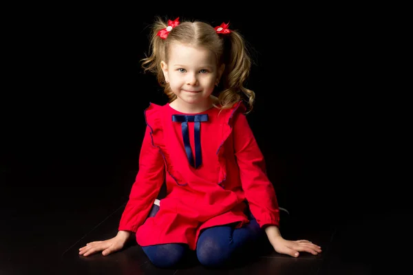 Adorable little girl in red dress sitting on floor — Stock Photo, Image