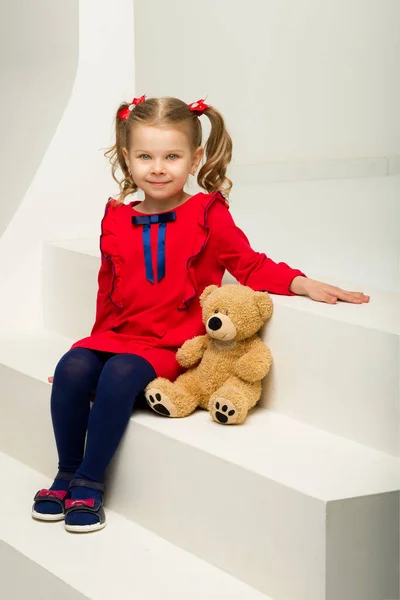 Kleines Mädchen sitzt mit Teddybär auf Treppe — Stockfoto