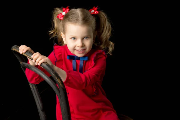Χαριτωμένο ξανθό κοριτσάκι κάθεται σε ξύλινη καρέκλα — Φωτογραφία Αρχείου