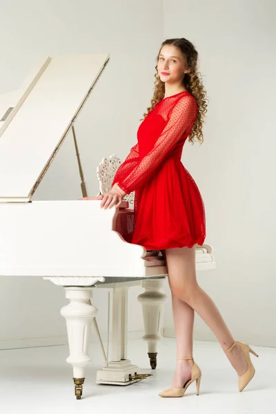 Feliz sorrindo jovem mulher de pé no piano de cauda — Fotografia de Stock