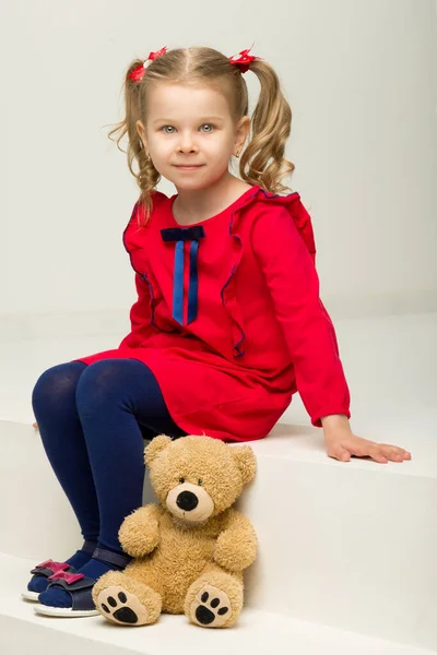 Klein meisje zit op de trap met teddybeer — Stockfoto