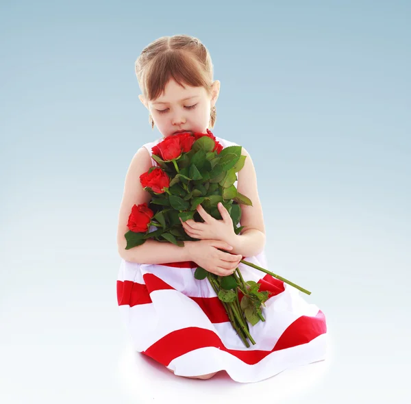 Doce menina cheirando um buquê de rosas vermelhas . — Fotografia de Stock