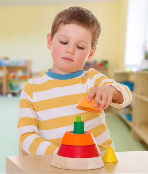 Boy collects colored pyramid — Stock Photo, Image