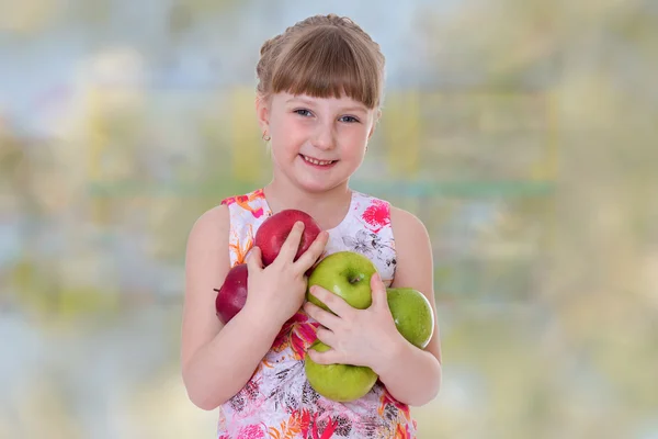 Glad flicka som håller en hel del äpplen. — Stockfoto