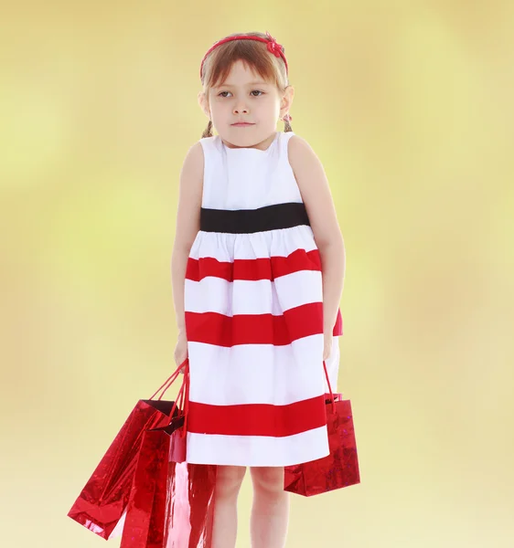 Kleines Mädchen geht mit roten Päckchen einkaufen. — Stockfoto