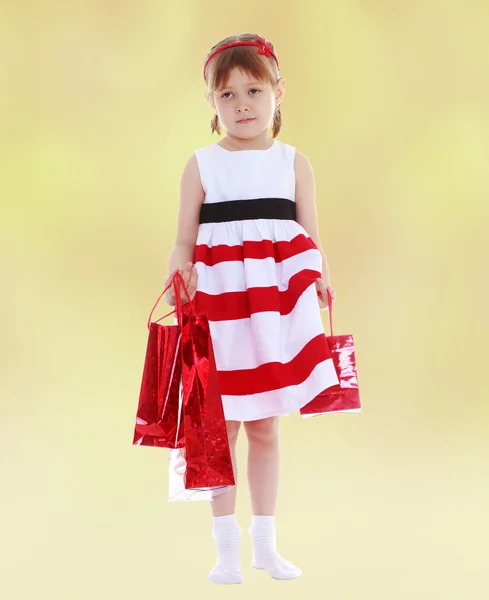 Kleines Mädchen geht mit roten Päckchen einkaufen. — Stockfoto