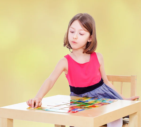 Meisje schoolmeisje zit aan een tafel — Stockfoto