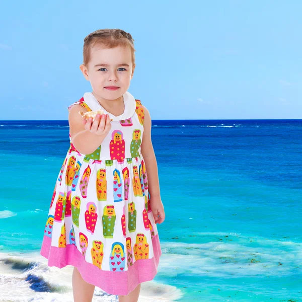Söt liten flicka på stranden visar — Stockfoto