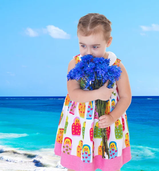 Affascinante bambina sulla spiaggia che profuma grande mazzo di blu f — Foto Stock