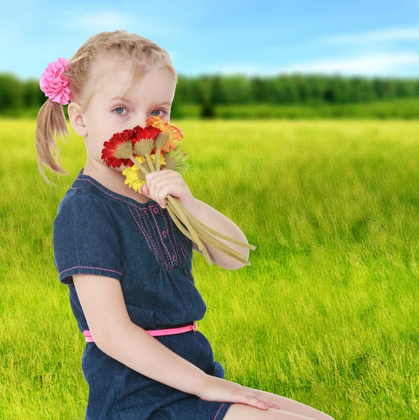 Girl in a field smelling flowers. — Stock Photo, Image