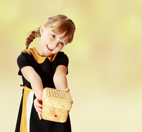 Girl holding at arms length wicker basket. — Stock Photo, Image