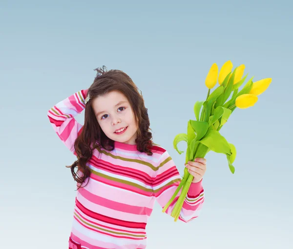 Adorable petite fille tenant un bouquet de tulipes jaunes . — Photo