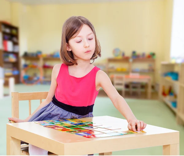 Menina encantadora senta-se em uma mesa — Fotografia de Stock