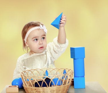 Hooked little girl playing with pyramid. clipart