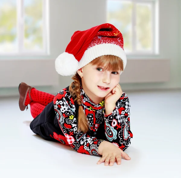 Little girl in santa claus hat ale a lesson. — Stock Photo, Image