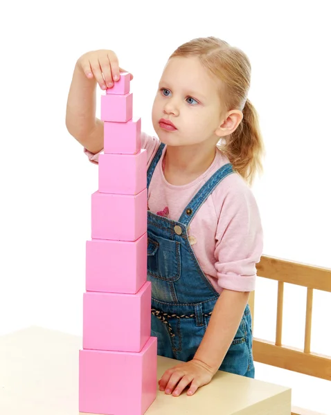 Little girl collects the pink pyramid. — Stock Photo, Image