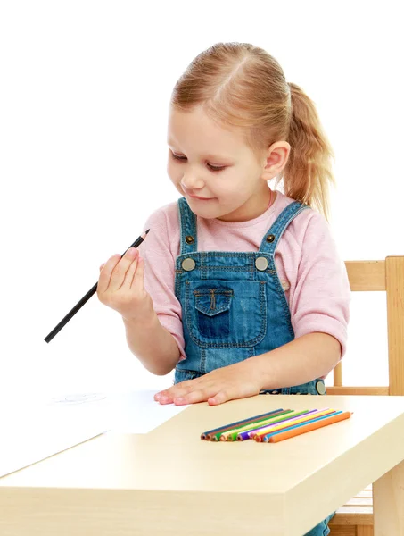 Meisje trekt potloden zitten aan de tafel. — Stockfoto