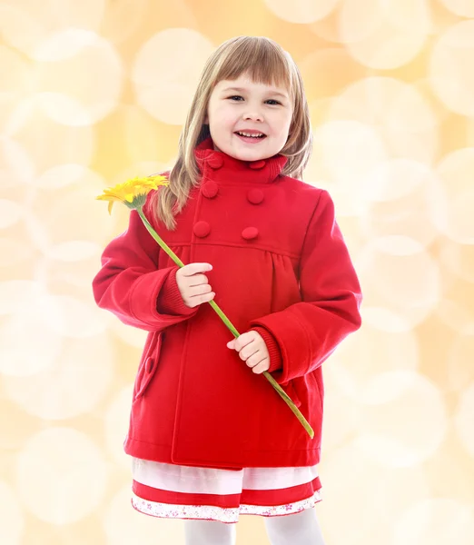 Petite fille en manteau rouge et tenant des fleurs . — Photo