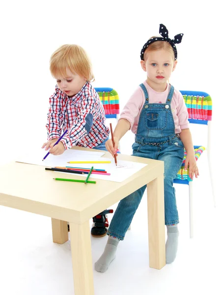 Flicka och pojke sitter vid bordet drar. — Stockfoto