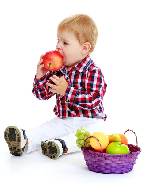 Liten pojke med en korg med frukt. — Stockfoto