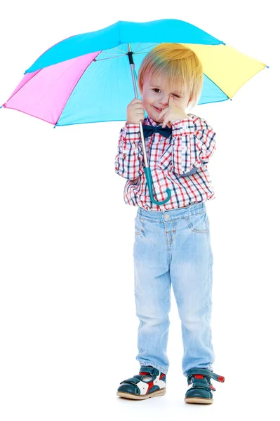 Kleine jongen staat onder een kleurrijke paraplu. — Stockfoto