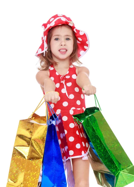 Little girl holds up a lot of big bright holiday packages. — Stock Photo, Image