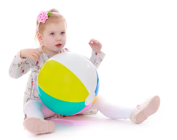 Kleines Mädchen sitzt auf dem Boden mit einem großen aufblasbaren Ball. — Stockfoto