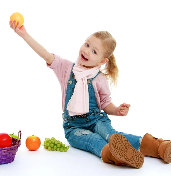Little girl holding her at arms length apple. — Stock Photo, Image