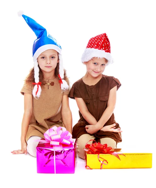 Zwei süße Schwestern in Weihnachtsmützen überlegen Geschenke. — Stockfoto