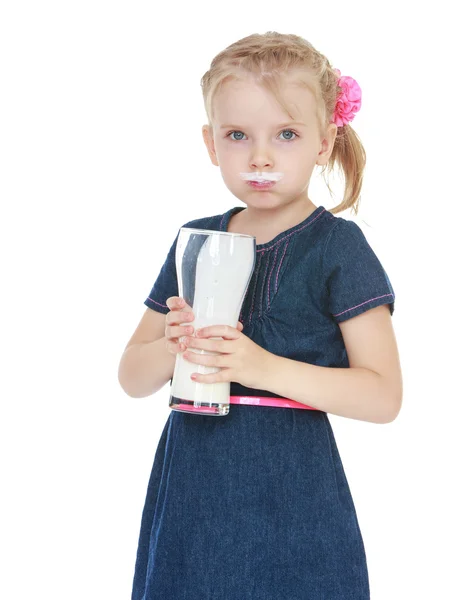 Маленькая девочка пьет из большого стакана молока . — стоковое фото