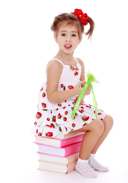 Beautiful little girl sitting on colorful books in hand wand. — Stock Photo, Image