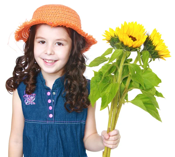 Hermosa niña en un sombrero y sosteniendo flores . — Foto de Stock