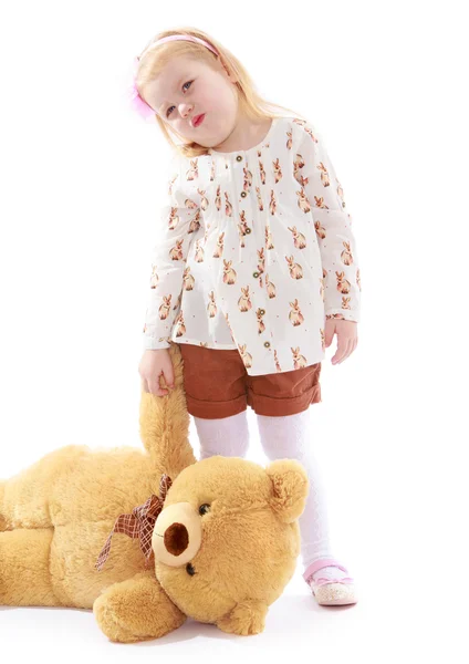 Sad little girl holding a teddy bear paw. — Stock Photo, Image