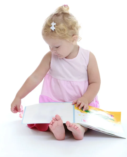 Adorable niña sentada descalza en el suelo y leyendo un —  Fotos de Stock