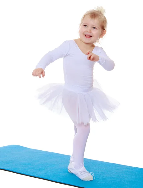 Lilla idrottsman i vit kostym hoppning på mattan. — Stockfoto