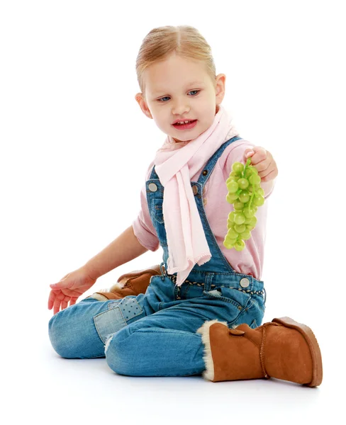 Girl in denim overalls sitting on the floor and holding a bunch — Stock Photo, Image