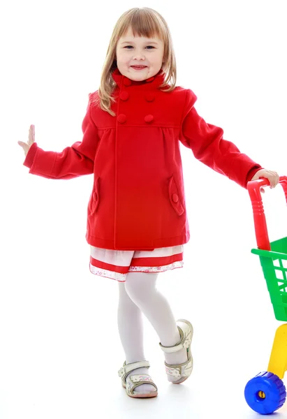 Fashionabla blond liten flicka med en vagn i butiken. — Stockfoto