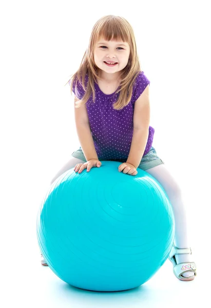 Flickan gör övningar på den stora blå bollen. — Stockfoto