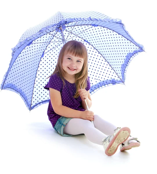 Lovely girl in summer shorts sitting under an umbrella. — Stock Photo, Image