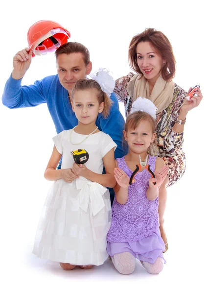 Cheerful family with two daughters holding various construction — Stock Photo, Image