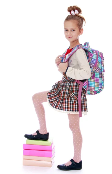 Chica feliz colegiala sosteniendo su pie en una pila de libros . — Foto de Stock