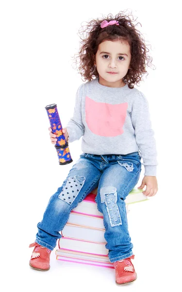 Pretty little girl sitting on the books. — Stock Photo, Image